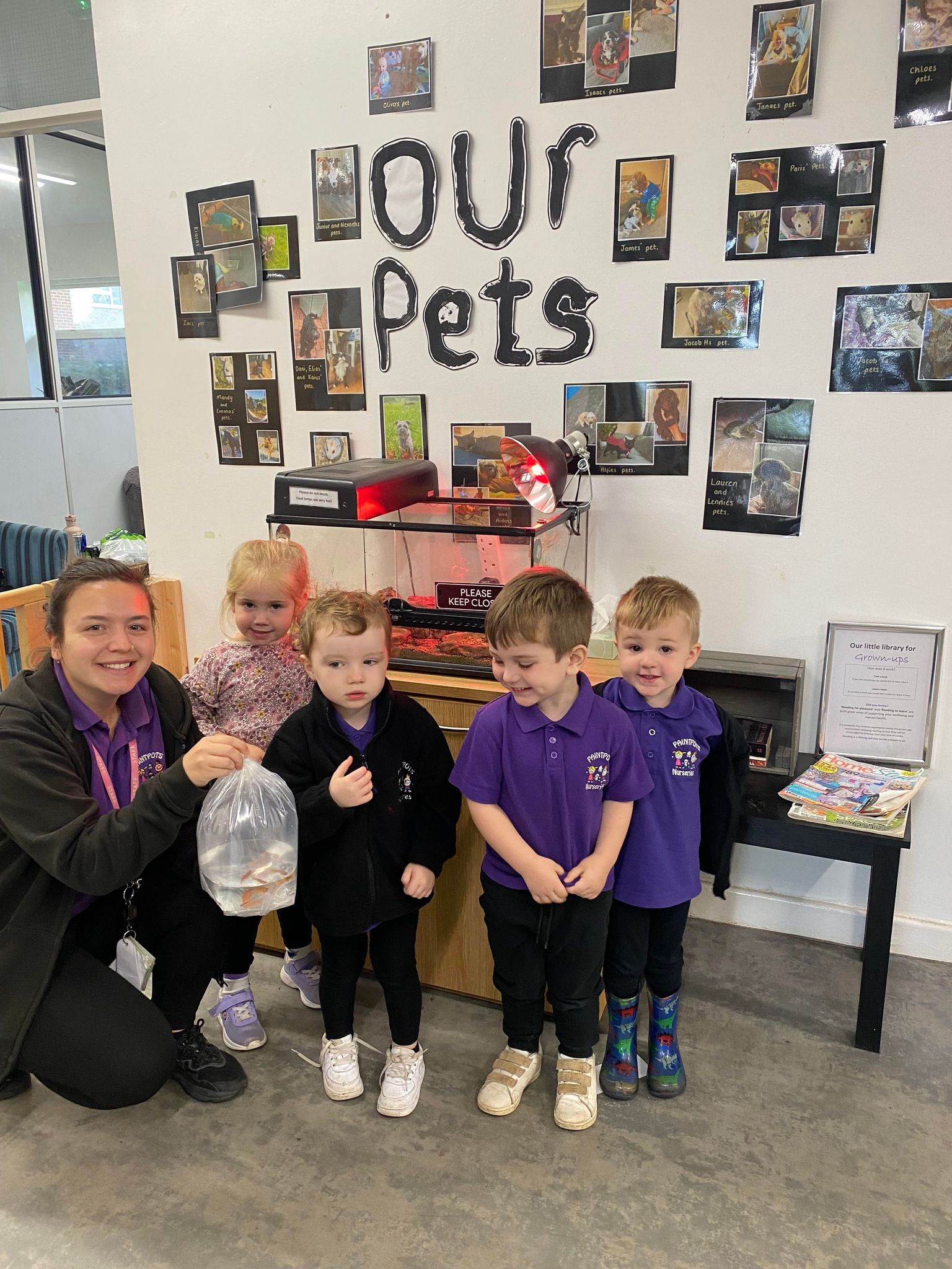 Children and a practitioner beside the nursery pets display