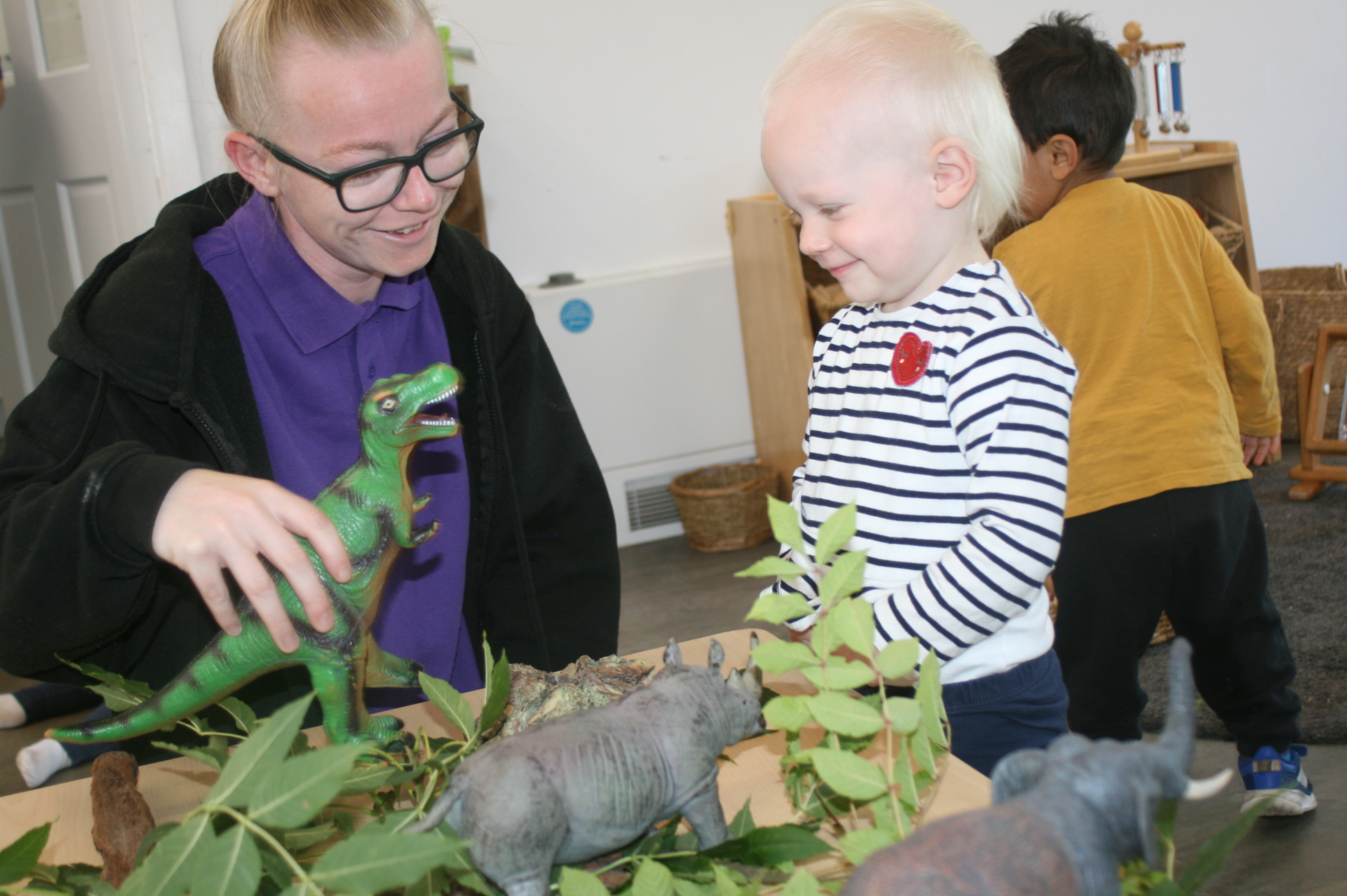 A Paintpots practitioner sharing animal figures with a child during play