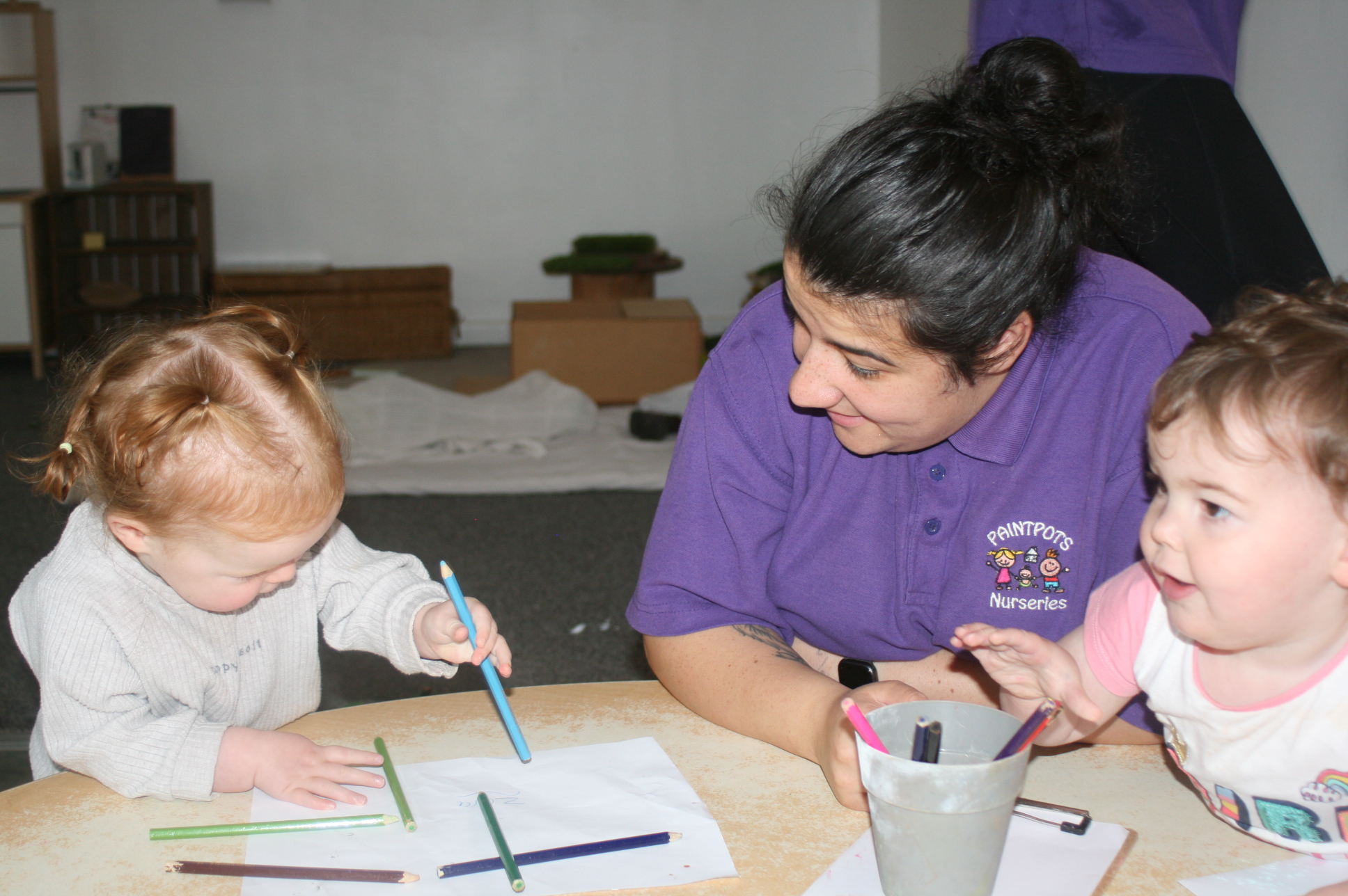 A practitioner drawing with two children at a table