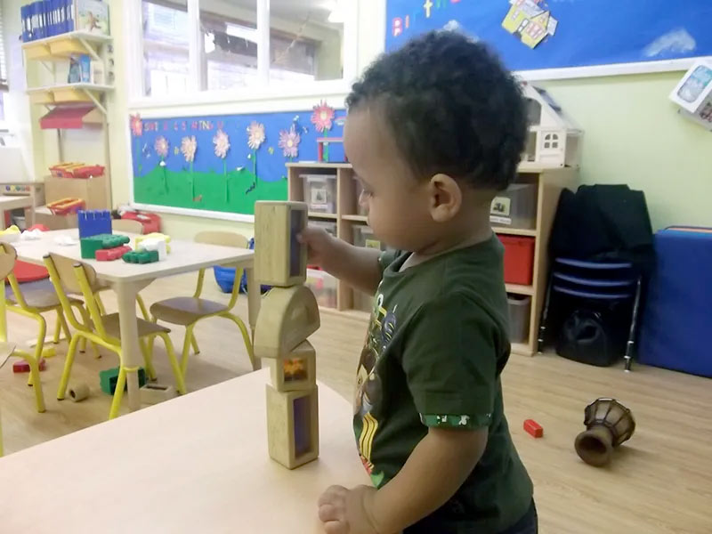 A child building with wooden blocks in the nursery