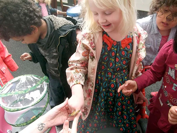 Children looking at a small creature during outdoor play